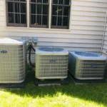 Three outdoor residential Carrier air conditioning condenser units installed beside a home for central cooling and HVAC climate control.