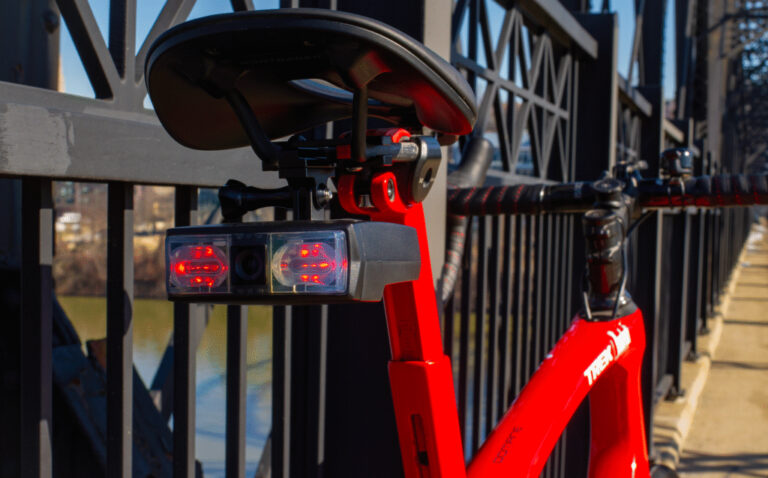 Close-up of a smart bicycle equipped with an AI-powered rear safety camera and illuminated warning lights mounted beneath the saddle.