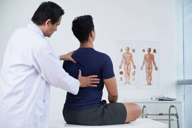 Doctor checking spine of a young man within the annual medical examination