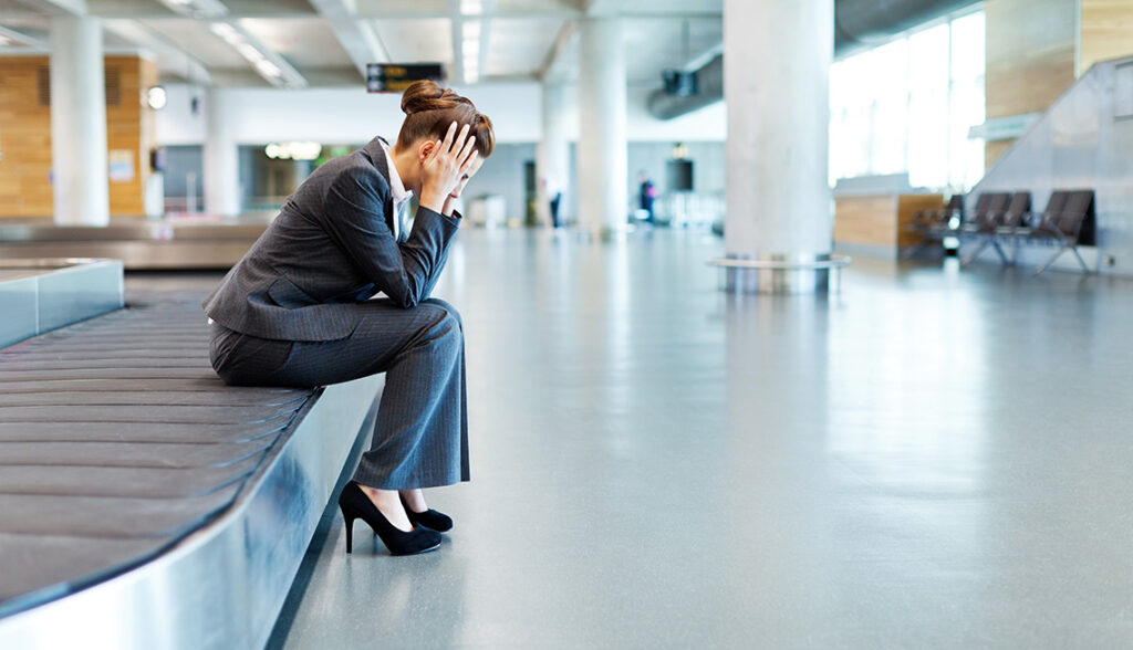 Frustrated Businesswoman Sitting at Baggage Claim