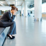 Frustrated Businesswoman Sitting at Baggage Claim