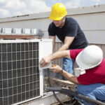 HVAC technicians repairing an outdoor air conditioning unit to improve cooling performance and system efficiency.