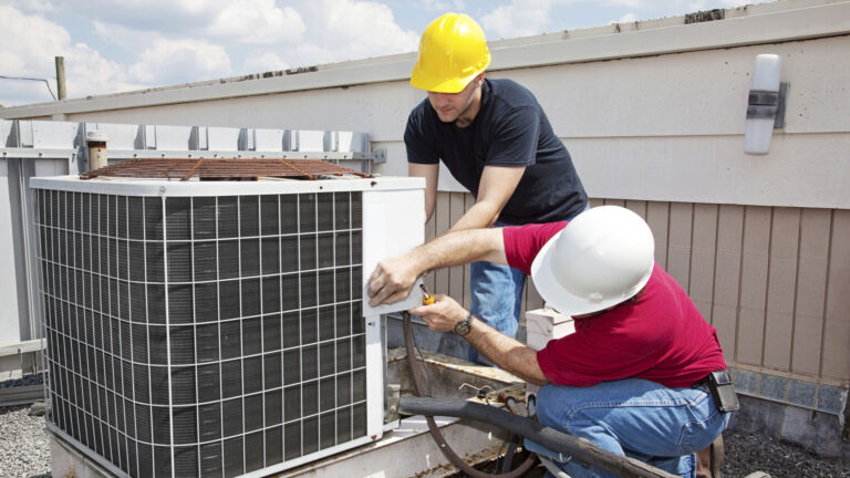 HVAC technicians repairing an outdoor air conditioning unit to improve cooling performance and system efficiency.