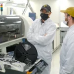 Engineers monitoring automated SMT manufacturing equipment in an electronics production facility