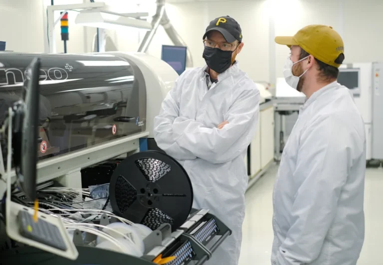 Engineers monitoring automated SMT manufacturing equipment in an electronics production facility
