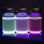 Three vials of cadmium sulfide (CdS) quantum dots glowing in blue, purple, and pink under ultraviolet light