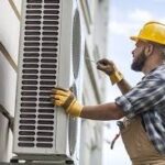 HVAC technician inspecting and servicing an outdoor air conditioning condenser unit while performing maintenance.