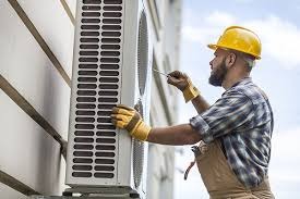 HVAC technician inspecting and servicing an outdoor air conditioning condenser unit while performing maintenance.