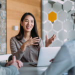 A team discussing strategic marketing services around a laptop in a modern office meeting room.