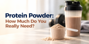 Protein powder in a scoop beside a shaker bottle for daily protein intake