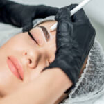 Beautician doing tattooing eyebrow dring permanent make up.