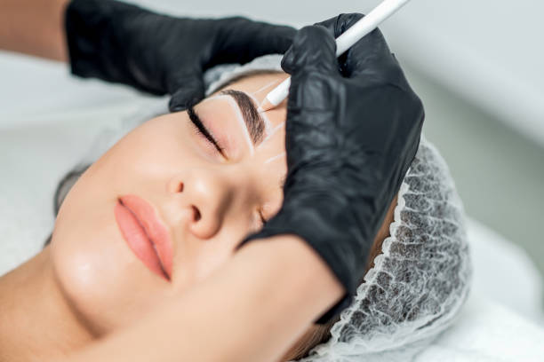 Beautician doing tattooing eyebrow dring permanent make up.