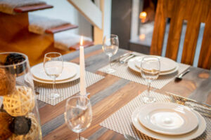 Table in dining room set up with plates, glasses and candlelight.