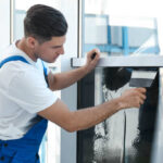 Professional worker tinting window with foil indoors