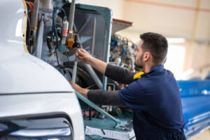 Aero mechanic fixing a helicopter in hanger. Aviation and safety concept.