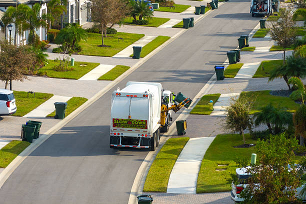 Garbage truck picking up trash bins on suburban street side.