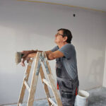 Skilled worker leaning on a ladder, planning painting work