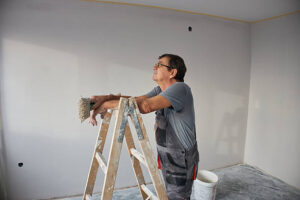 Skilled worker leaning on a ladder, planning painting work