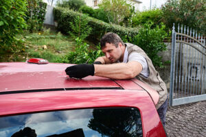 Man sanding a car roof, preparing the surface for painting